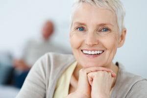 Smiling mature woman with husband in the background